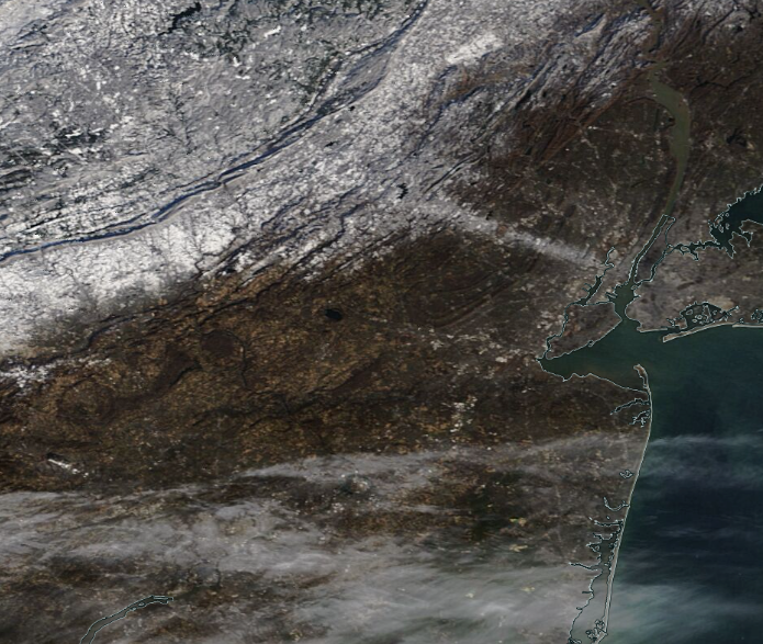 Figure 5. MODIS visible satellite image on the morning of December 12th. The previous evening’s squall path across north Jersey is seen compared to surrounding snow-free ground. Widespread snow cover is found to the northwest across northwest NJ, northeast PA, and part of NY. Cirrus clouds cover portions of South Jersey and southeast Pennsylvania (NASA). MODIS visible satellite image on the morning of December 12th. The previous evening’s squall path across north Jersey is seen compared to surrounding snow-free ground. Widespread snow cover is found to the northwest across northwest NJ, northeast PA, and part of NY. Cirrus clouds cover portions of South Jersey and southeast Pennsylvania (NASA).